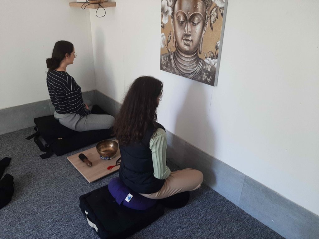 clients en position de méditation face a un mur
