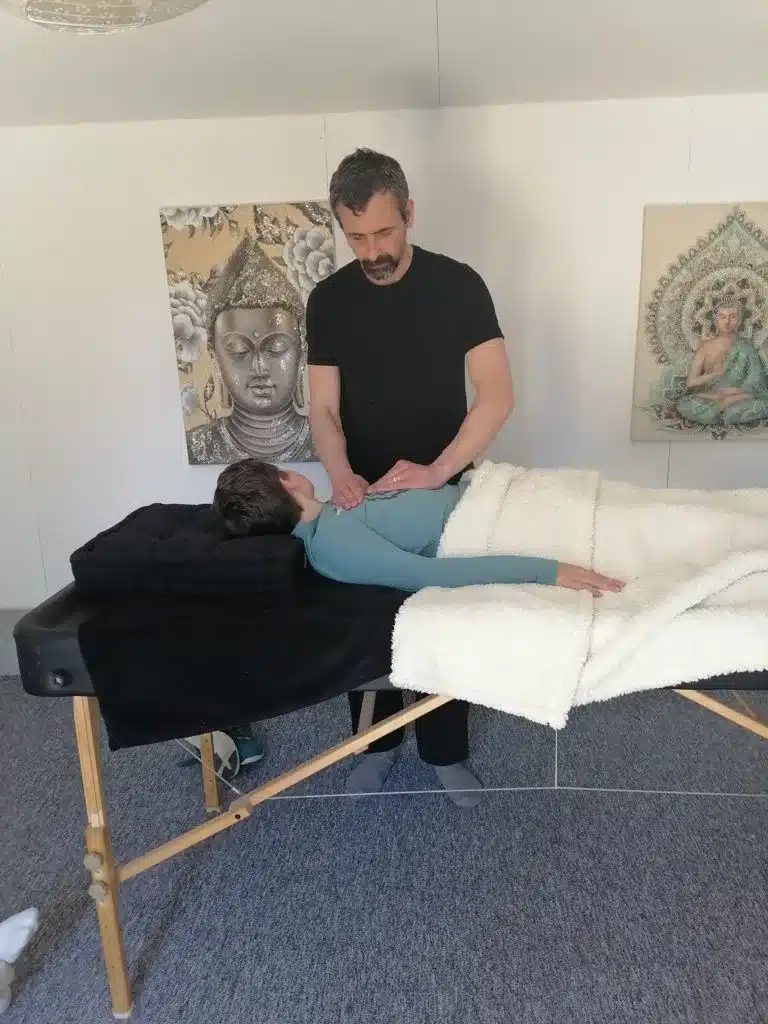 Praticien de Reiki en train de faire une séance de traitement énergétique sur un enfant sur une table de soin.